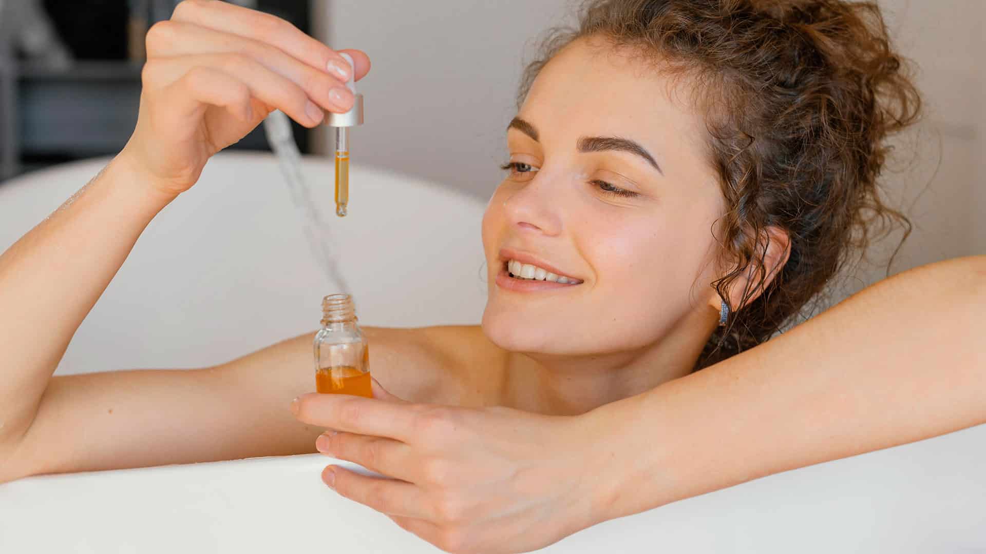 een vrouw in een badkuip met een flesje medicijnen.